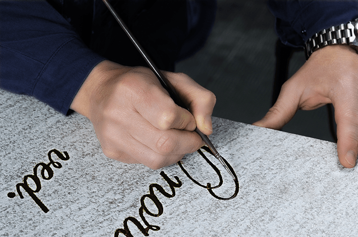 Photo d'un artisan marbrier qui peint une sépulture